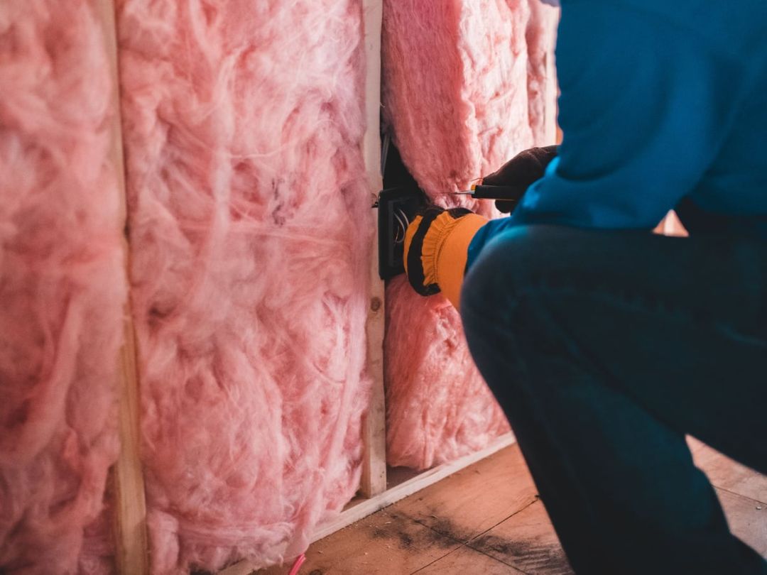 Handwerker mit Handschuhen dämmt eine Konstruktion mit Mineralwolle