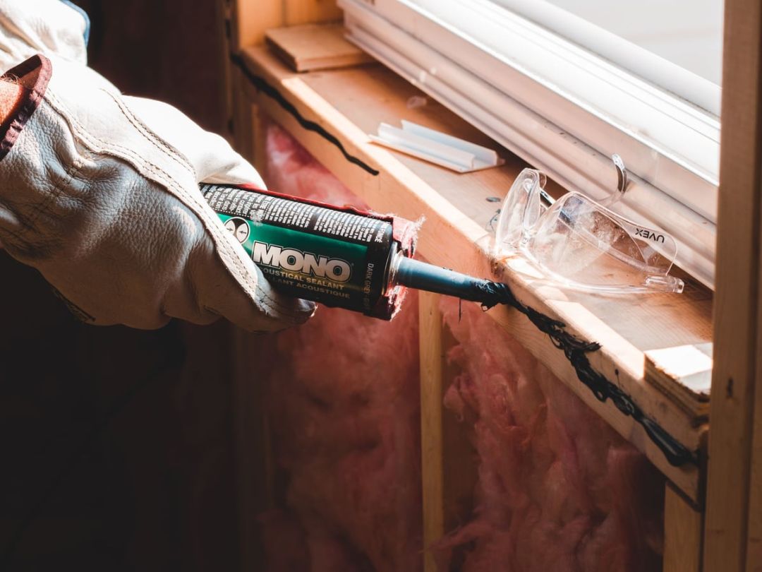 Handwerker zieht eine Dichtfuge am Anschluss eines eingebauten Fensters