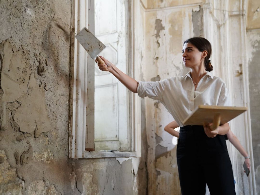 Person trägt frischen Putz auf eine Wand in einem alten Innenraum auf