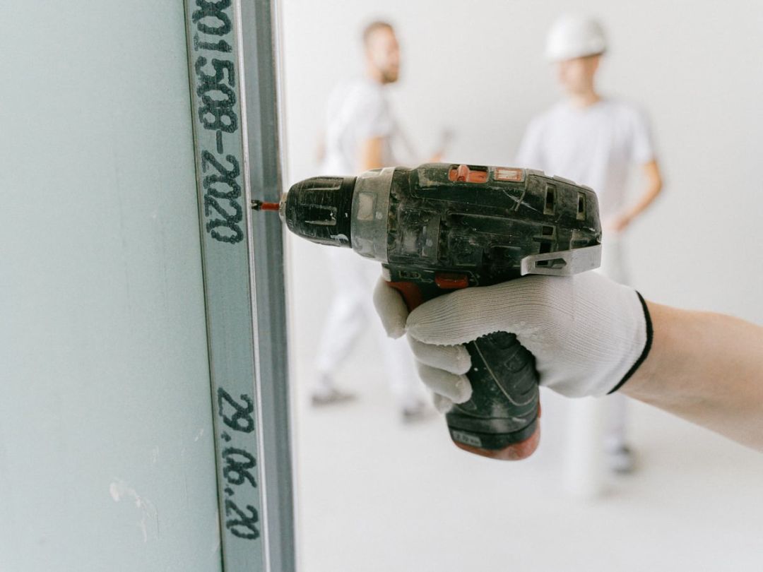 Handwerker verschraubt eine Gipsplatte auf einer Ständerkonstruktion