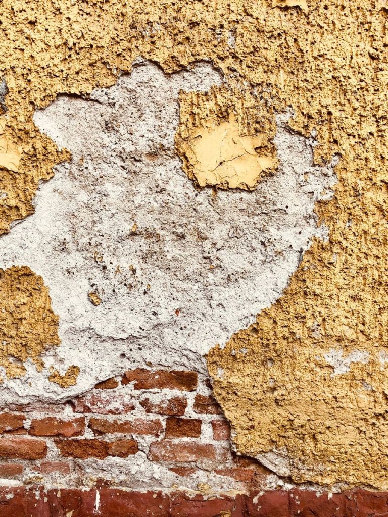 Freigelegte Altbauwand mit abblätterndem Putz und sichtbarem Ziegelmauerwerk